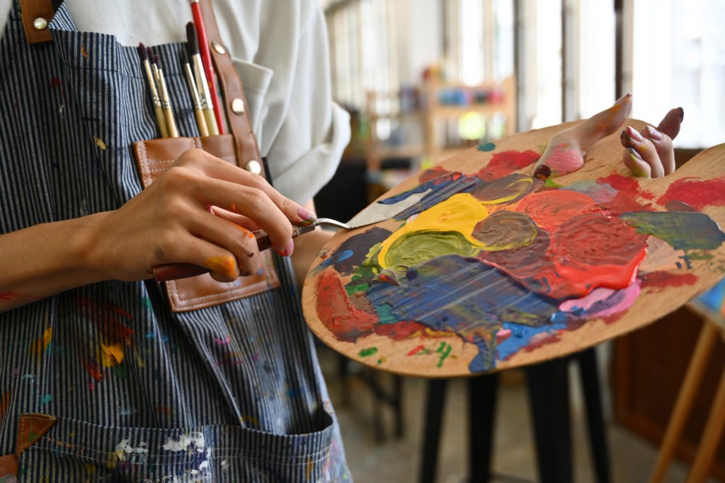 Nærbilde av en ung kreativ malers hånd som holder en fargepalett